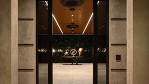 Ein modernes Interieur mit einem zentralen Tisch, eingelassener Beleuchtung und Blick ins Freie.