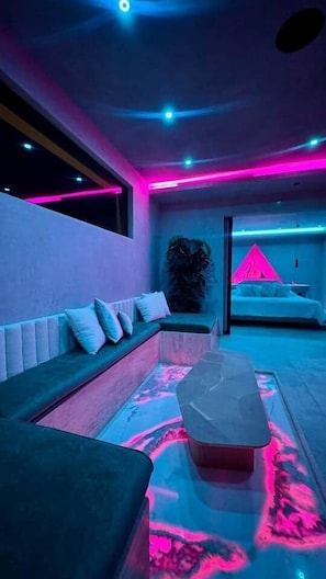 A modern bedroom with a bed, a seating area, and a small table.