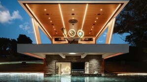 Ein modernes Gebäude mit Pool, Holzboden und Steinwänden.