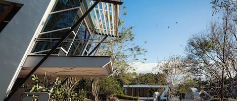 A modern building with a glass facade, a covered outdoor area, and a parking lot.