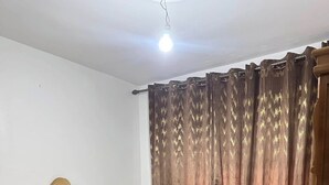 Ein Schlafzimmer mit Bett, Vorhängen und einer Deckenleuchte.