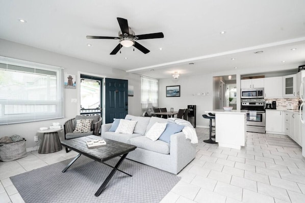 A modern living room with a sofa, coffee table, and a dining area.