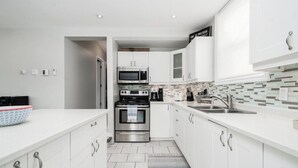 A modern kitchen with white cabinetry, stainless steel appliances, and a tiled backsplash. - Scenic Waterfront Cottage Retreat - Firepit & BBQ (Hanover)