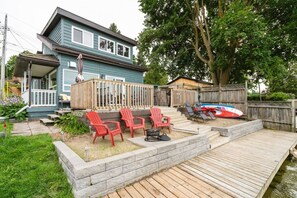 A house with a deck, outdoor seating, and a small boat.