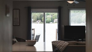 A room with a dining table, chairs, a television, and a ceiling fan. - Scenic Waterfront Cottage Retreat - Firepit & BBQ (Hanover)