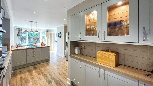 A modern kitchen with grey cabinets, a wooden countertop, and a built-in wine rack.