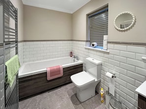 Een badkamer met een bad, toilet en wastafel.