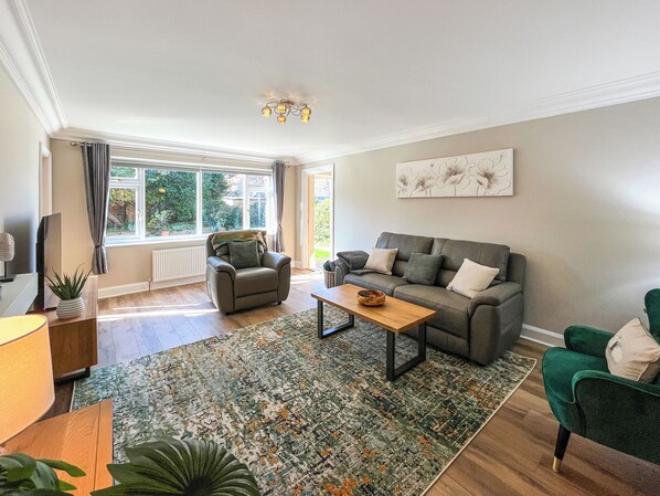 Een woonkamer met een bank, fauteuil, salontafel en een groot raam.