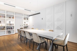 Ein moderner Konferenzraum mit einem langen Tisch, sechs Stühlen und eingebauten Regalen.