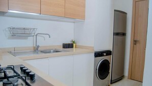 Une cuisine de taille réduite équipée d’une cuisinière à gaz, d’un évier, d’un lave-linge et d’un réfrigérateur.