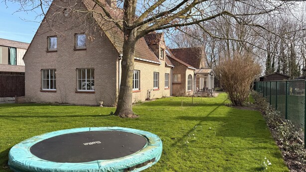 Ett hus byggt av tegel med en studsmatta på gården.