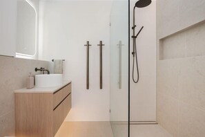 Ein modernes Badezimmer mit Duschkabine aus Glas, einem Holzwaschtisch und einem weißen Waschbecken.