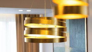 A modern chandelier with a cylindrical design, a grey sofa with cushions, and a painting on the wall. - Stay in a luxury apartment near Diocletian's Palace (Split)