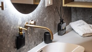 A bathroom with a marble sink, a gold faucet, a mirror, and a towel rack with folded towels. - Stay in a luxury apartment near Diocletian's Palace (Split)