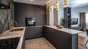 A modern kitchen with dark cabinetry, a stainless steel sink, and a central island with a bowl of fruit. - Stay in a luxury apartment near Diocletian's Palace (Split)