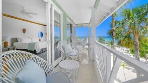 A balcony with wicker furniture, a bed, and a view of the beach. - Couples Negril - Adults Only (Negril)