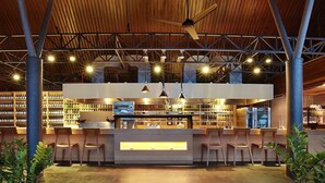 Un área de bar interior con techo de madera, varias luces colgantes y una barra central.