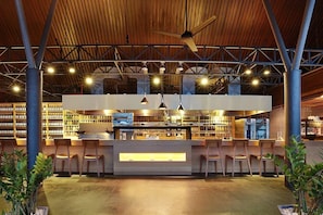 Un espace bar intérieur doté d’un plafond en bois, de plusieurs luminaires suspendus et d’un comptoir central.