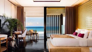 Une chambre d’hôtel moderne dotée d’un grand lit, d’un balcon avec vue sur l’océan, d’un petit coin repas et d’une télévision.