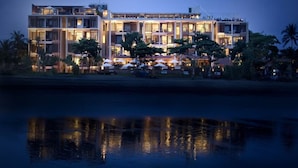 Un hôtel à plusieurs étages, doté de balcons, de sièges en plein air et dont l’image se reflète dans l’eau.