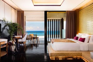 Une chambre d’hôtel moderne dotée d’un grand lit, d’un balcon avec vue sur l’océan, d’un petit coin repas et d’une télévision.