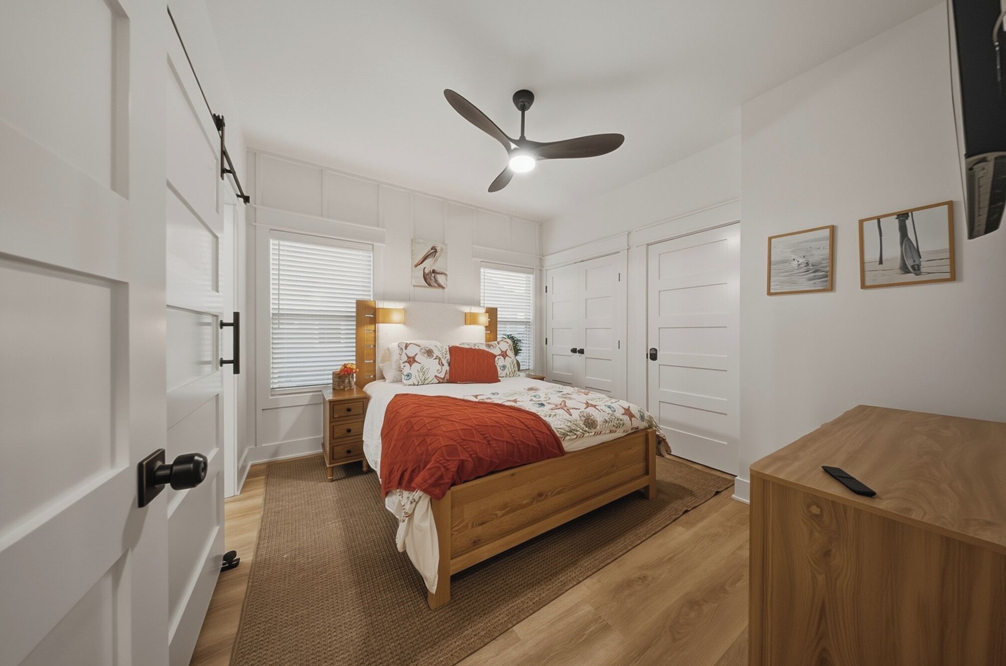 Ein Schlafzimmer mit Bett, Nachttischen, Deckenventilator, Schreibtisch und Kleiderschrank.