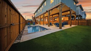 Ein zweistöckiges Haus mit Pool, Holzterrasse und Sitzbereich im Freien.