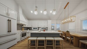Eine moderne Küche mit weißen Schränken, einer zentralen Kochinsel mit Sitzgelegenheiten, einem Essbereich mit Holztisch und Stühlen sowie Pendelleuchten.