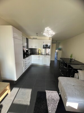 A modern kitchen with white cabinets, a central island, and a dining area with a table and chairs. - Natural paradise for hikers & cyclists Aachen border triangle (La Calamine)