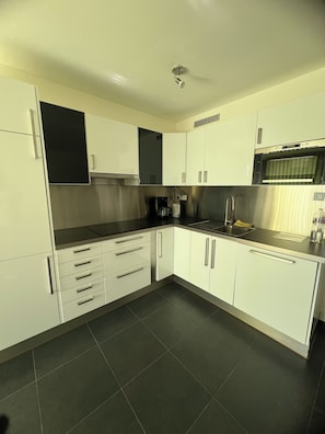 A modern kitchen with white cabinets, a stainless steel range, and a built-in oven.