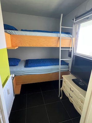 Habitación con literas y un televisor sobre un aparador.