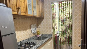 A kitchen with wooden cabinets, a stainless steel refrigerator, a granite countertop, and a tiled backsplash.