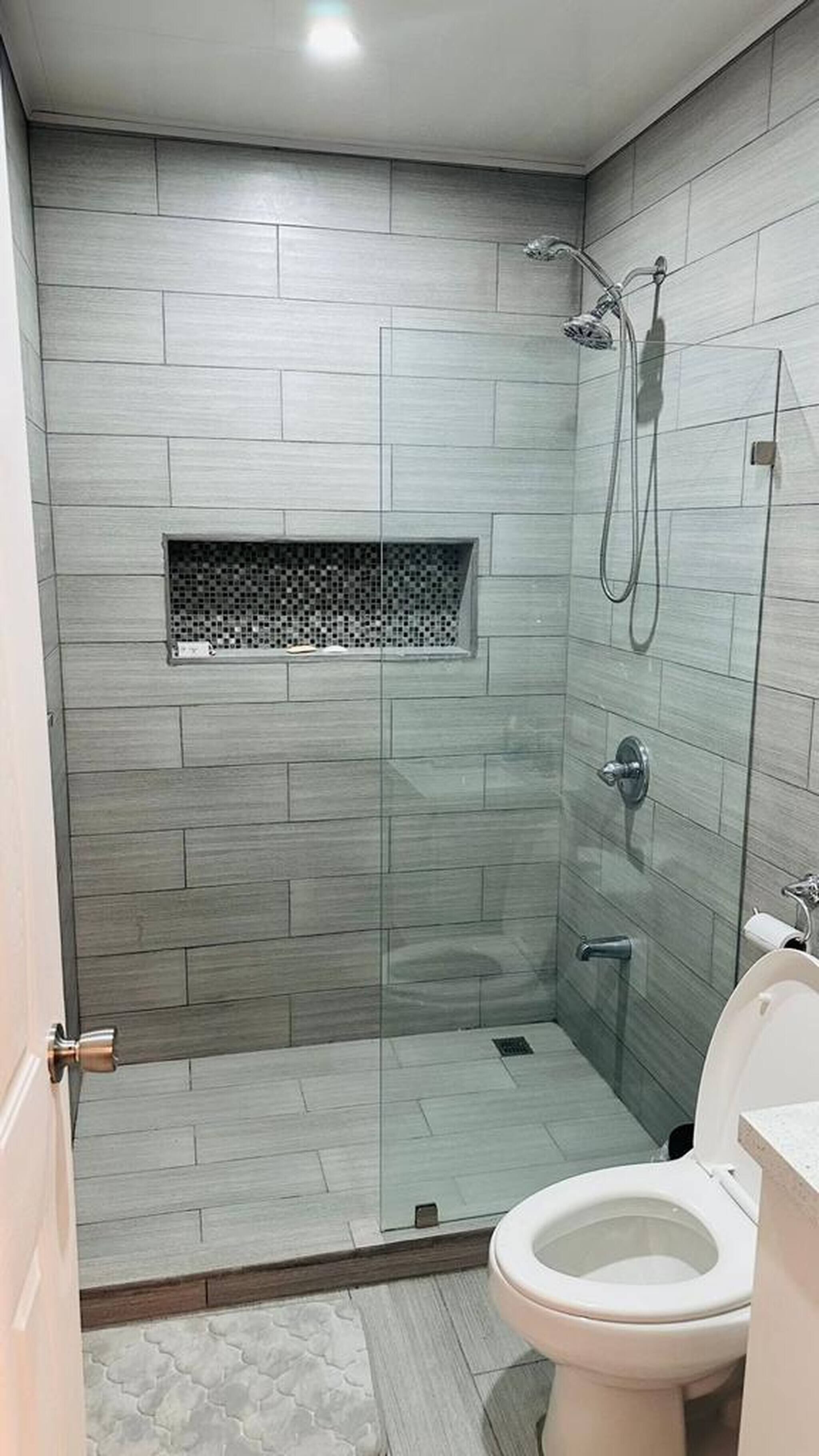 A modern bathroom with a glass-enclosed shower, a toilet, and a sink.