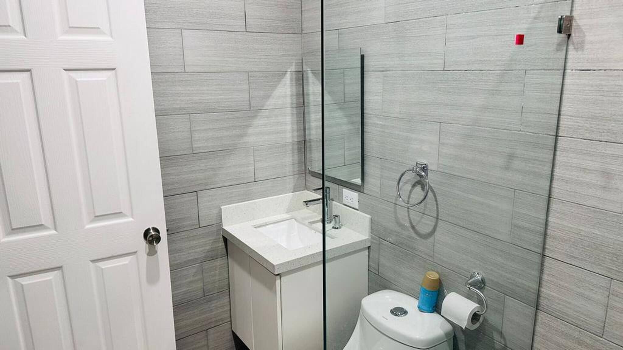 A bathroom with a white sink, a toilet, and a glass shower enclosure.