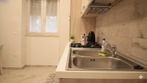 A kitchen with two stainless steel sinks, a gas stove, a coffee maker, and a bottle of dish soap. - A due passi dagli Scavi con parcheggio gratuito e Wi-Fi (Pompei)