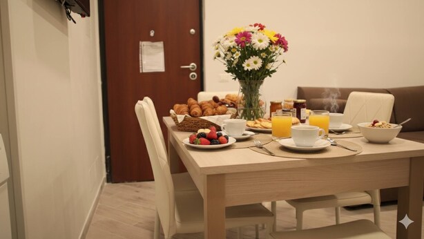 A breakfast setup with croissants, fruit, juice, and a vase of flowers on a wooden table in a hotel room. - A due passi dagli Scavi con parcheggio gratuito e Wi-Fi (Pompei)