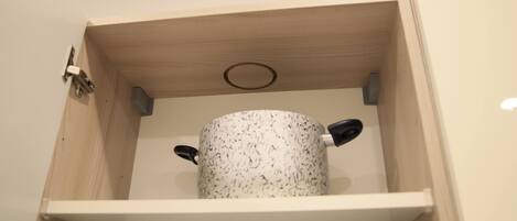A wooden cabinet with a white interior, containing a white object with black handles.