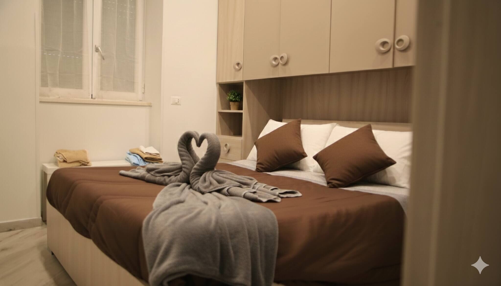 A bedroom with a bed, a window, a bedside table, and a wardrobe.