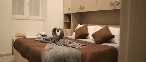 A bedroom with a bed, a window, a bedside table, and a wardrobe.