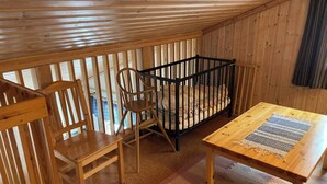 A cozy room with wooden walls and a sloped ceiling. There is a crib, a wooden table, and two chairs. - beautiful mountains in Sälen högfjället Sweden (Sälen)