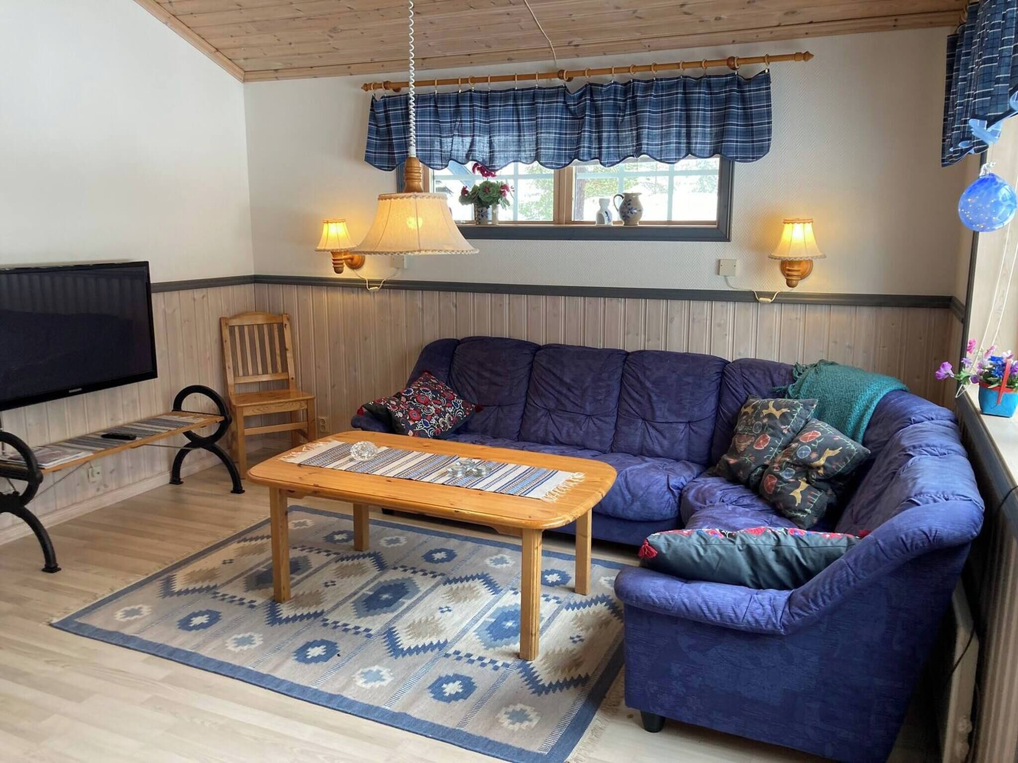 A cozy living room with a blue sofa, a wooden coffee table, and a TV on a stand.
