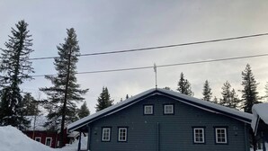 A two-story cabin with a steep roof, surrounded by snow-covered ground and tall evergreen trees. - beautiful mountains in Sälen högfjället Sweden (Sälen)