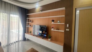Un salon moderne doté d’un téléviseur à écran plat, d’étagères intégrées et d’un mur d’accent en bois.