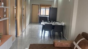 Un vaste espace de vie comprenant un canapé marron, une table à manger avec des chaises, un téléviseur à écran plat et un ventilateur de plafond.