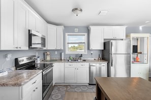 A modern kitchen with white cabinets, stainless steel appliances, a granite countertop, and a window with blinds. - Amazing little fishing cabin on the water with a boat ramp in Everglades City (Everglades City)