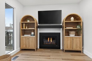 Ein modernes Wohnzimmer mit Kamin, Holzregalen und einem Flachbildfernseher.