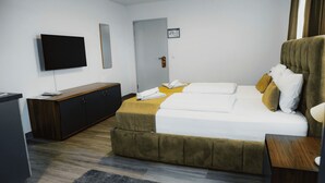 Une chambre d’hôtel avec un lit, une télévision, une armoire en bois et une porte.