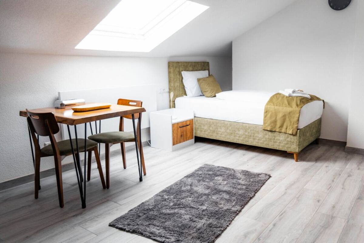 A small, modern room with a bed, a desk, and a chair.