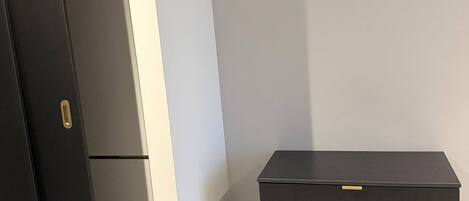 Et værelse med en sort garderobe, en hvid væg og et beige tæppe.