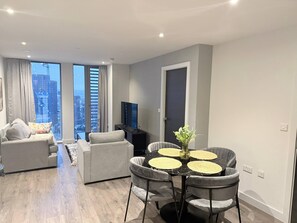 Ein modernes Wohnzimmer mit Essbereich, großen Fenstern und Blick auf die Stadt.